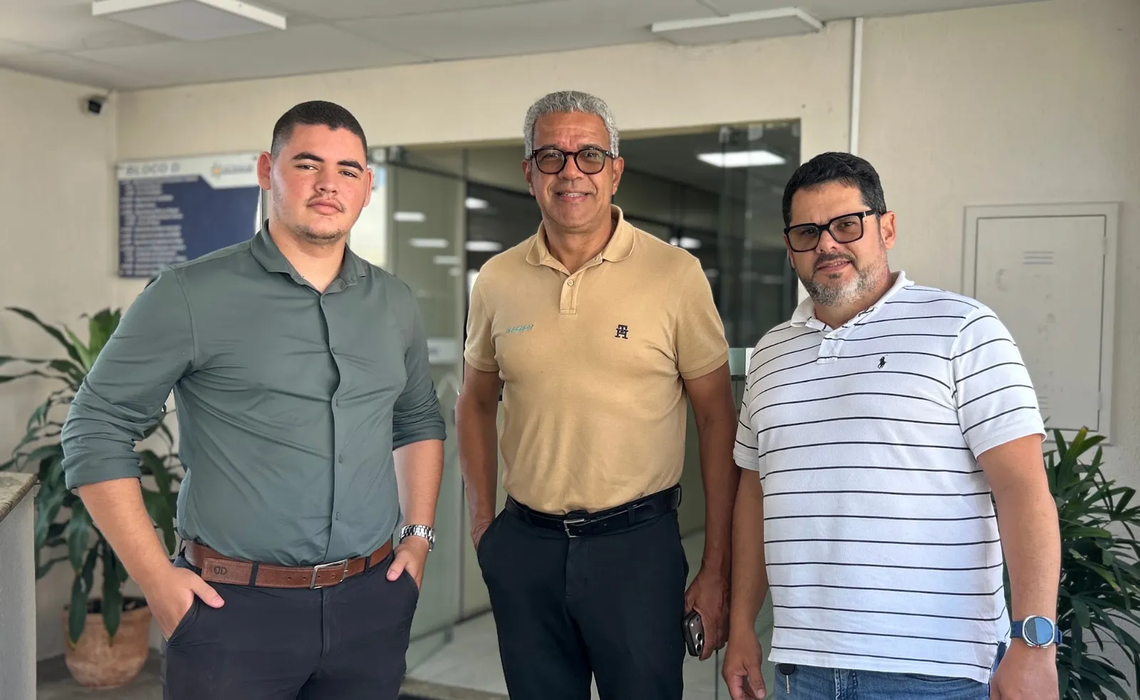 Três integrantes da equipe técnica reunidos na entrada de um bloco da sede do DETRAN-SE