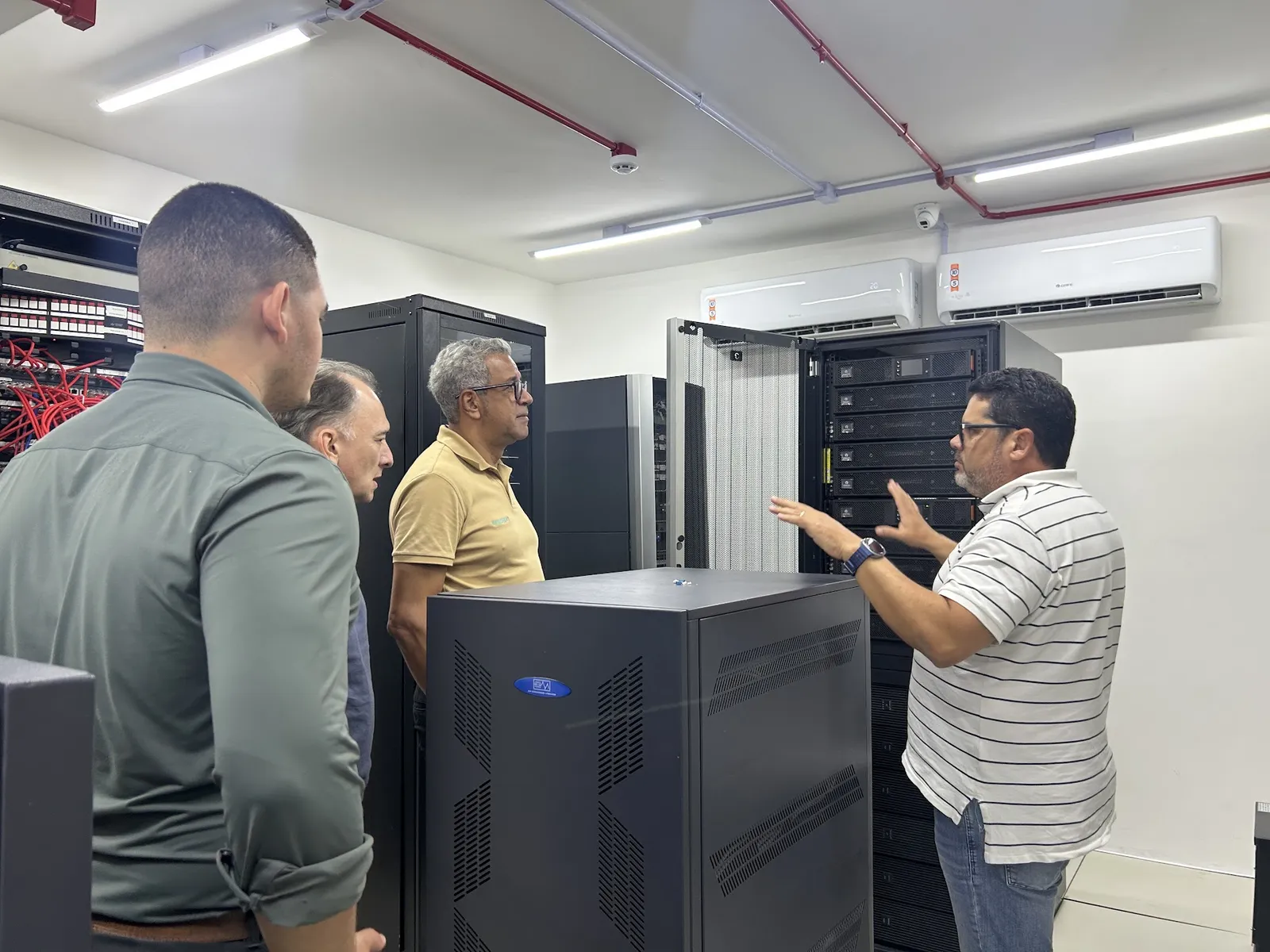 Equipe técnica conversa diante de racks abertos no data center do DETRAN-SE
